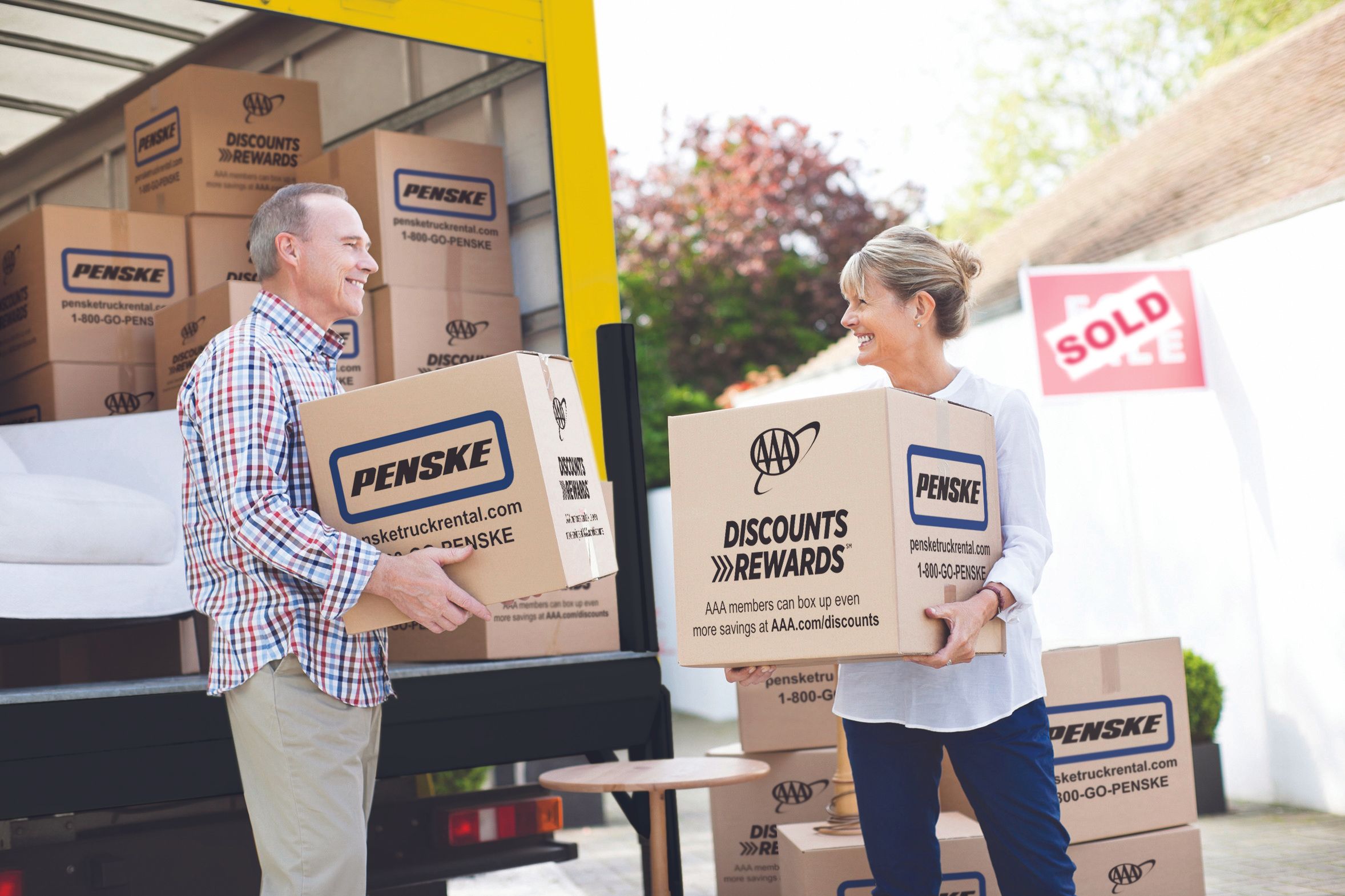 A man and woman load Penske boxes onto a moving truck.